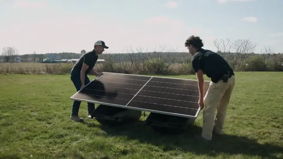Two PowerField Energy crew members setting a solar panel in a field